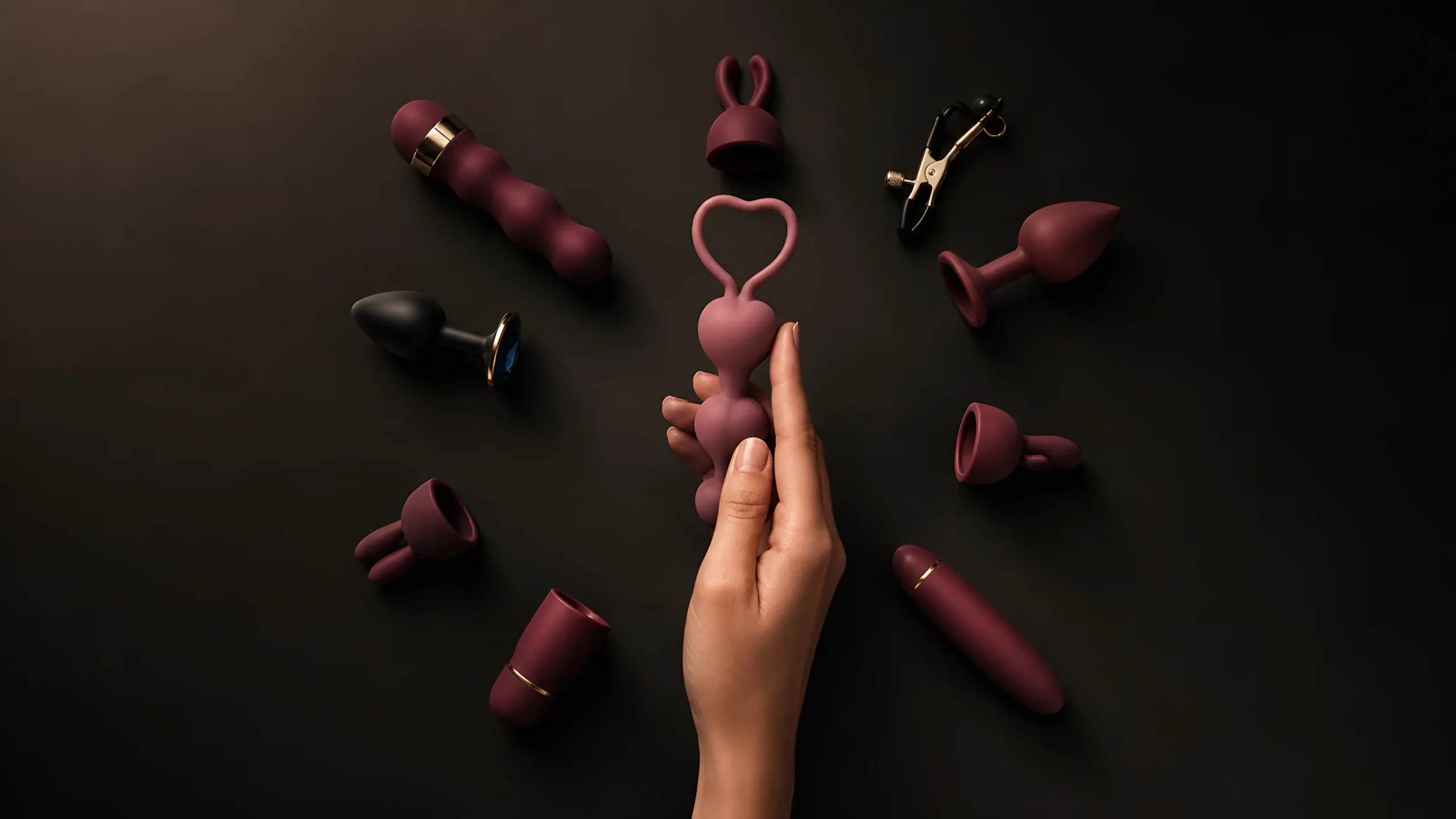 Quiet vibrators and discreet pleasure products arranged on a dark background, with a hand holding a compact pink vibrator